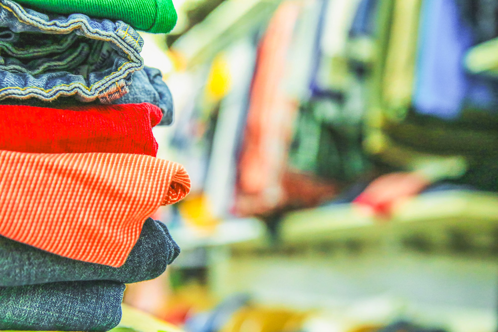 Folded clothes in the foreground. Clothes rail with clothes in the background